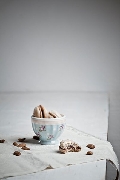 Bowl with macaroons while almonds scattered