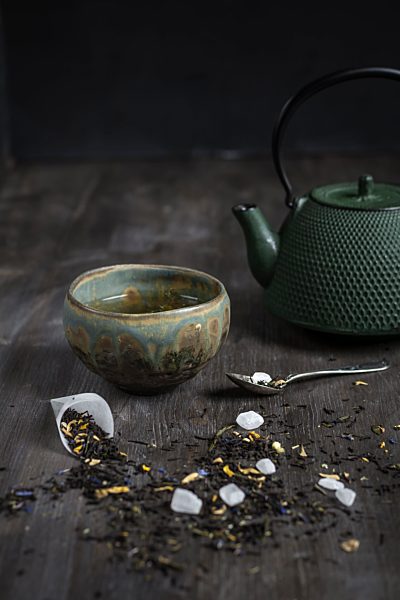 Japanese tea pot and bowl with tea leaves on wooden table, studio shot
