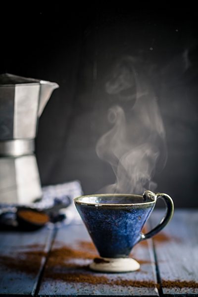 cup on cafetiera on table with coffee powder