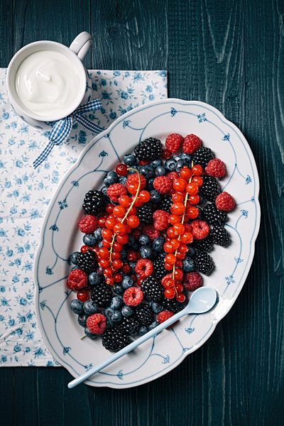 Berries on serving plate with cup of yoghurt