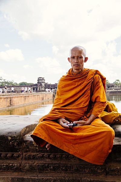 Cambodia, Siem Reap, Angkor, monk sitting infront of Angkor Wat