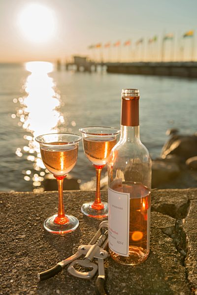 Germany, Bavaria, Nonnenhorn, Bottle of wine and glasses on wall at shipping pier