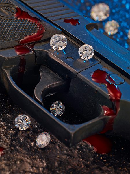 Trigger of pistol with diamonds and blood, close-up