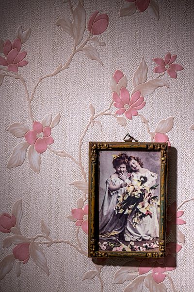 Picture frame with old photograph hanging on wallpaper with pink floral design