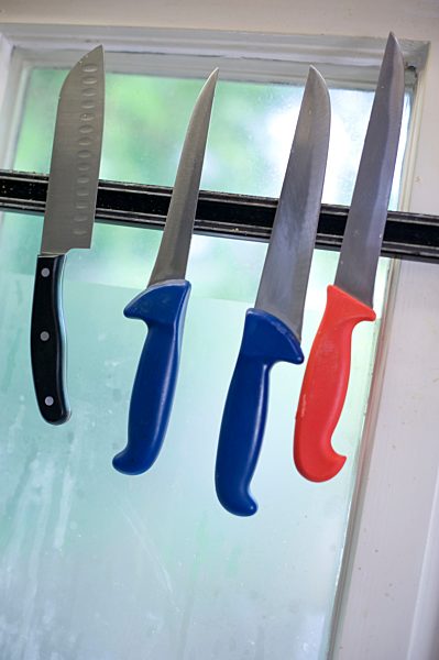Knives hanging on a magnetic strip in the kitchen of a restaurant