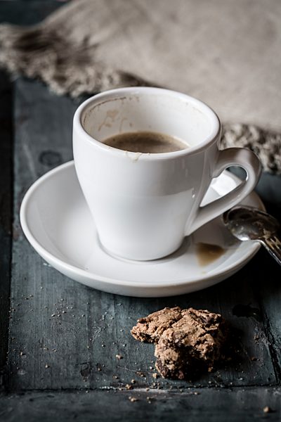 Cup of coffee and leftover of chocolate cookie on grey wood