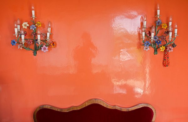 Two old wall lamps hanging at glossy red wall