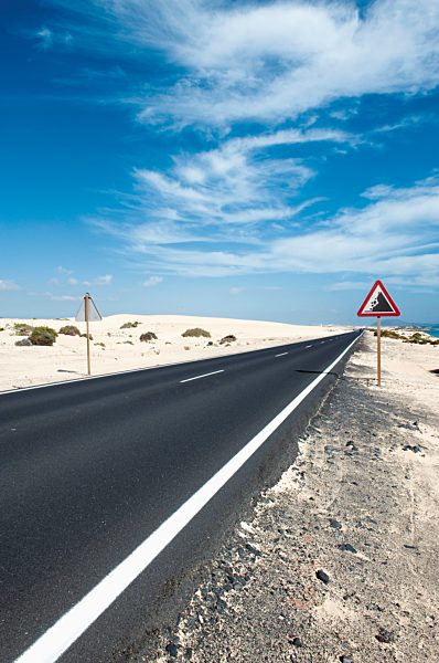Spain, Fuerteventura, Corralejo, Parque Natural de Corralejo, view of empty road and road sign