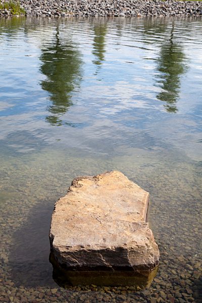 Germany, North Rhine-Westphalia, Dortmund-Hoerde, waterside of Phoenix See with stone and reflection of trees