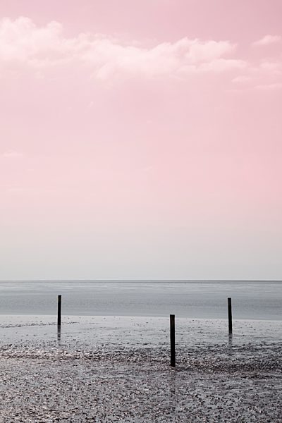 Germany, Lower Saxony, East Friesland, Norddeich, three poles at low tide by twilight