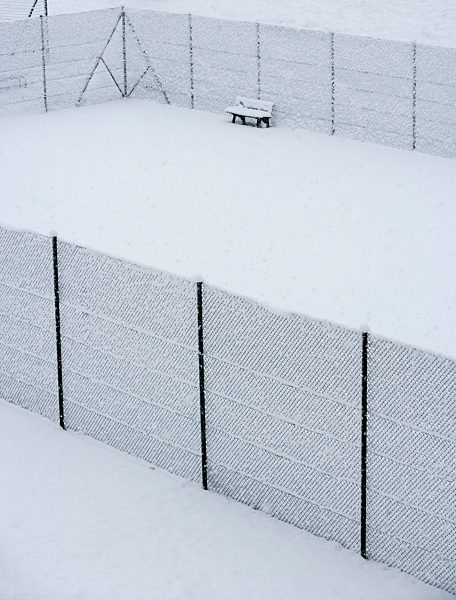 Austria, Styria, Bench and fence covered with snow at tennis court