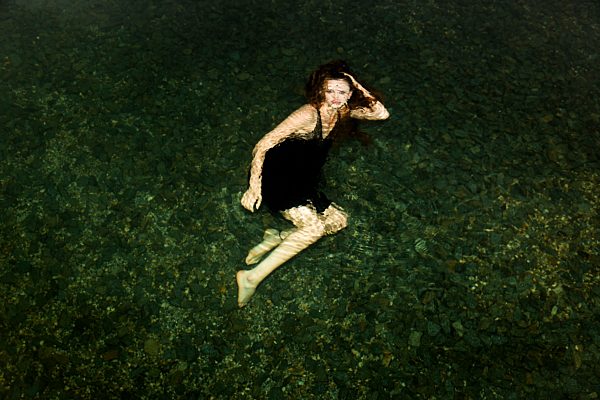 Germany, Young woman under water, looking to camera