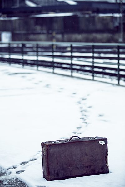 Old suitcase standing in snow on platform