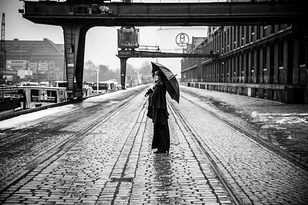 Germany, Berlin, woman with umbrella watching buildings at industrial harbour