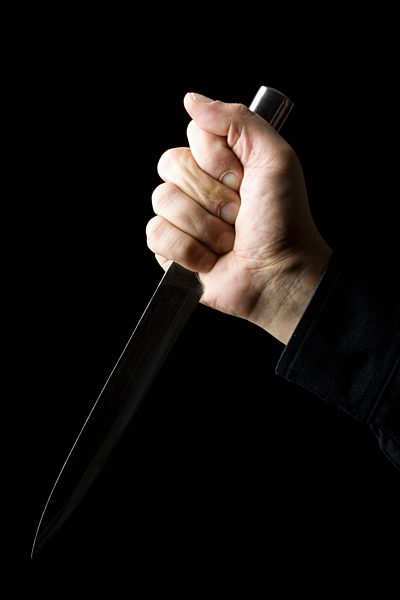Mid adult man holding knife against black background