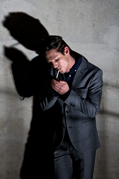 Germany, Bavaria, Young man smoking in dark corner