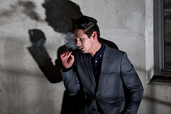 Germany, Bavaria, Young man smoking in dark corner