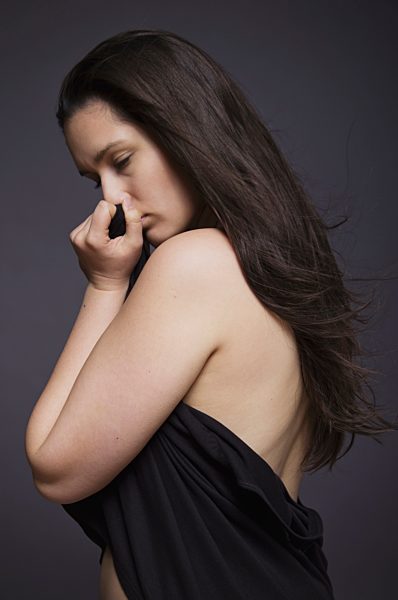 Young woman covering with clothes, close up