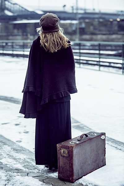 Germany, Berlin, woman with umbrella and old suitcase waiting at platform in winter