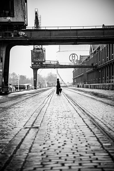 Germany, Berlin, woman with umbrella watching buildings at industrial harbour
