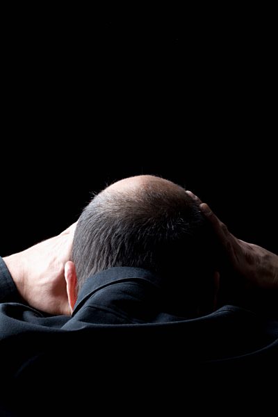 Mid adult man beats his hands over his head against black background