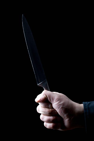 Mid adult man holding knife against black background