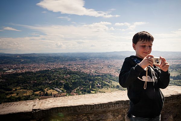Italy, Tuscany, Fiesole, boy holding his camera looking at photos