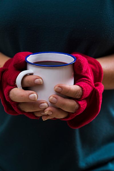 Hands of a woman holding glass with hot wine punch