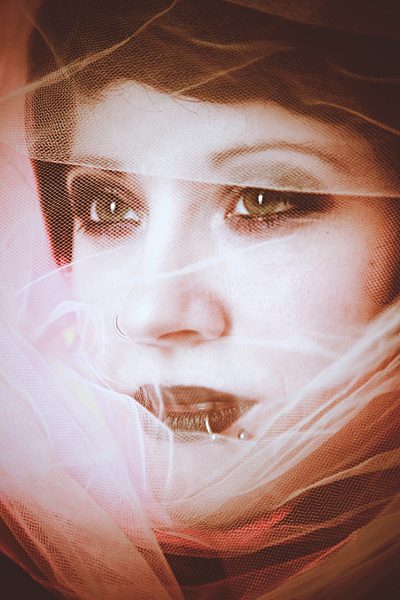 Portrait of young woman with veil and piercings, partial view