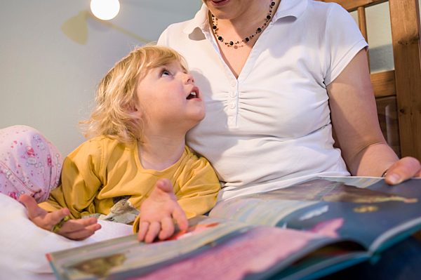 Mother teaching daughter in bedroom