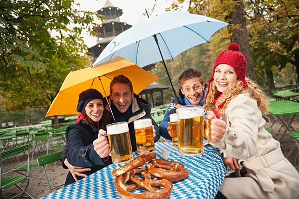 Germany, Bavaria, English Garden, Four persons sitting in rainy beer garden