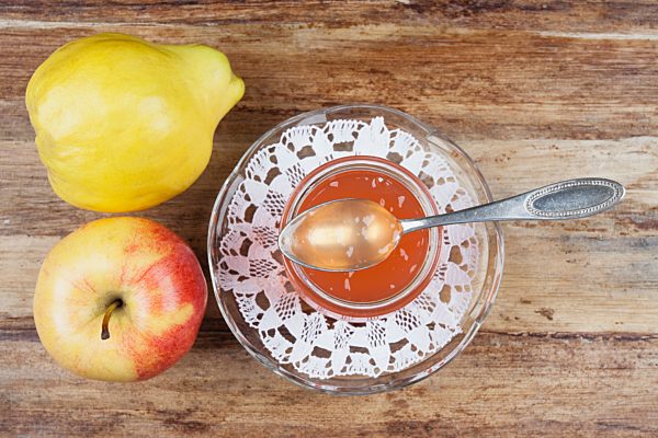 Quince and apple jam in jar with fruit on table