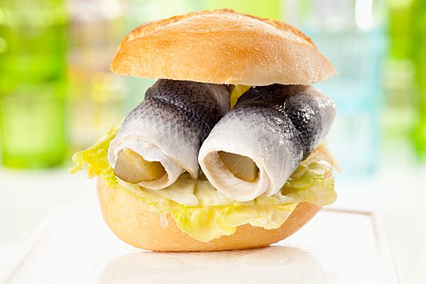 Bread roll with rollmop herring and pickled gherkin, close up
