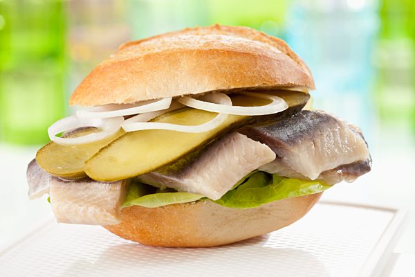 Bread roll with matjes herring, pickled gherklin and onions, close up