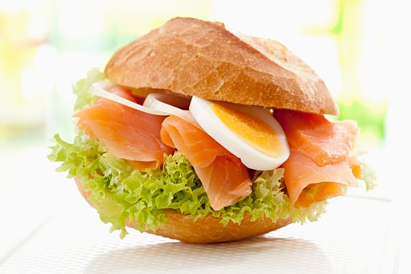 Bread roll with smoked salmon, egg and onions, close up