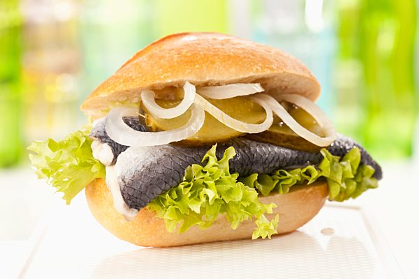 Bread roll with bismark herring, pickled gherkin and onions, close up