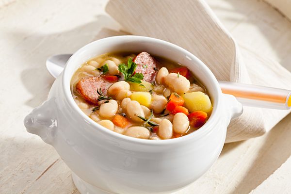 Bowl of white bean soup with smoked sausage, close up