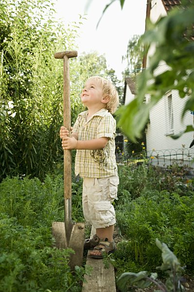 Germany, Bavaria, Boy holding shovel in garden