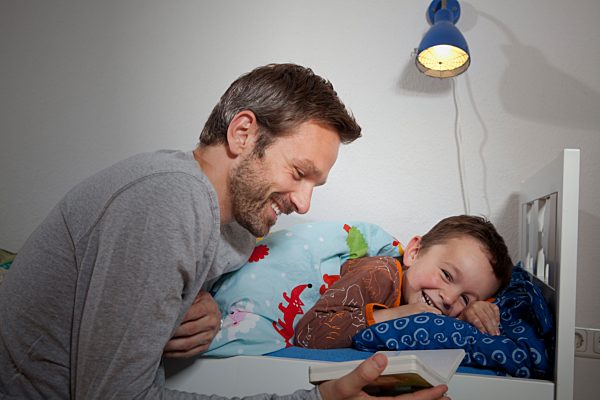 Germany, Berlin, Father reading book while son sleeping