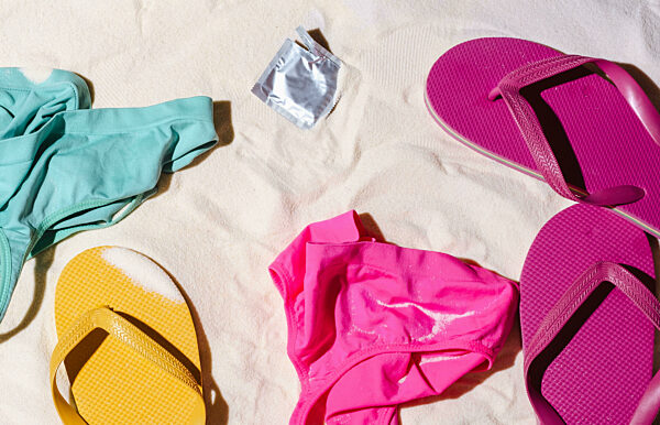 Flip flops and thong on sandy beach with condom summer concept