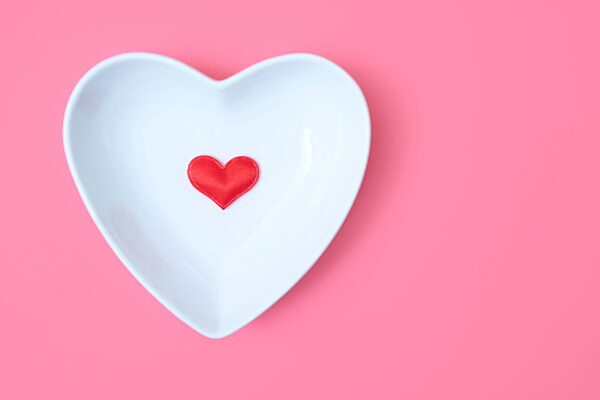 Heart-shaped bowl with red heart on pink background for Valentine's Day