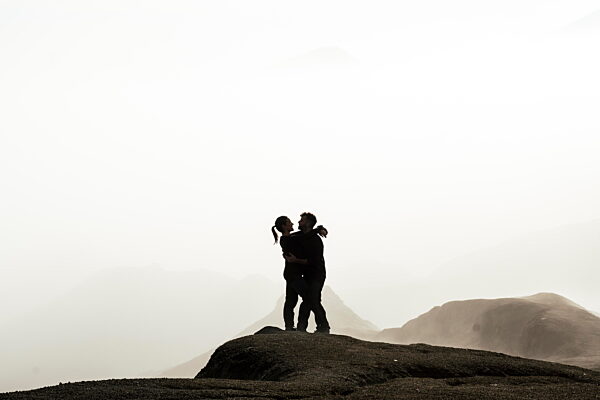 Couple embracing on foggy Java landscape showing romance and connection