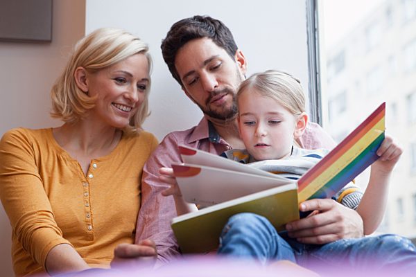 Father and mother reading picture book to daughter