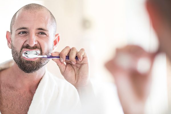 Mirror image of man brushing his teeth