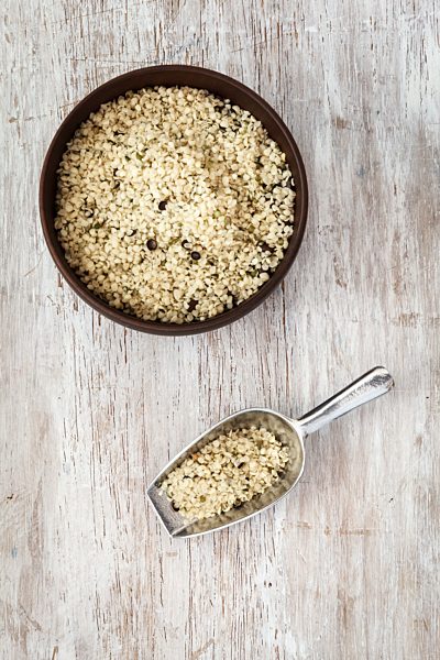 Peeled hamp seeds, wooden bowl and spoon