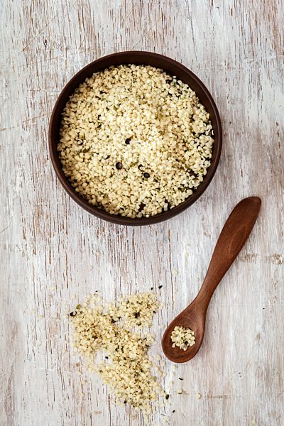 Peeled hamp seeds, wooden bowl and spoon