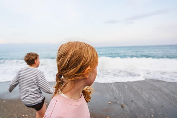 Siblings enjoying playful shared moment on overcast sandy beach