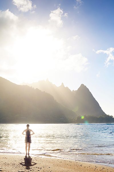 USA, Hawaii, Hanalei, woman standing on Haena Beach, View to Na Pali Coast in the evening light