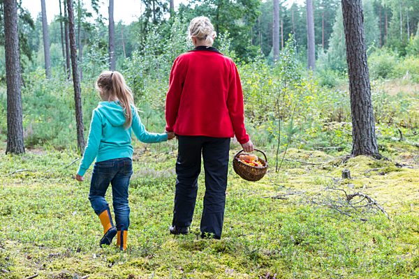 Estonia, mother and daughter with basket of mushrooms in a forest