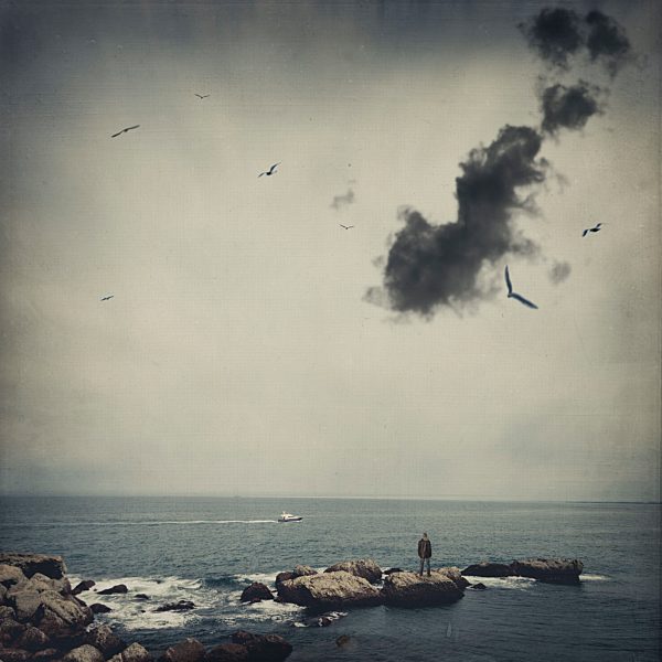 France, Biarritz, man standing on stone at seaside